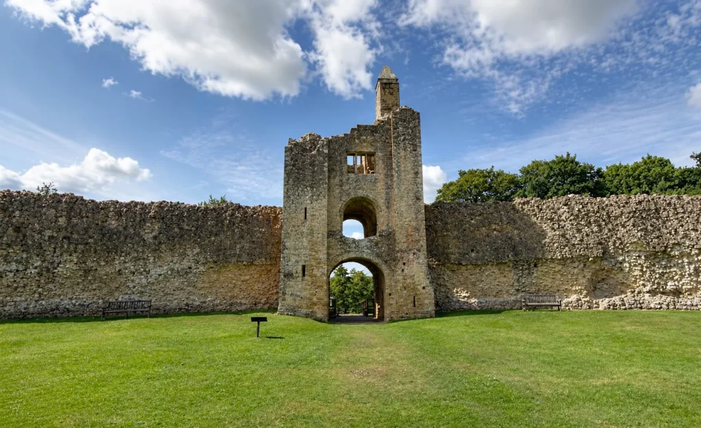 Sherborne Old Castle ruins with stone walls, green lawn and blue sky overhead.