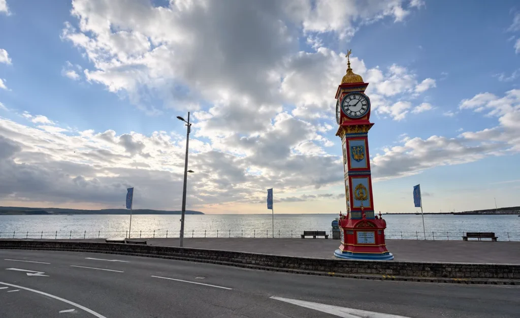 Weymouth Jubilee Clock Tower on the seafront, with the beach, promenade and sea in the background.